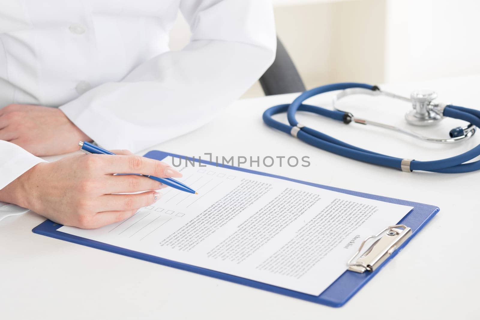 Female doctor hands writing on sheet in a clipboard with a pen