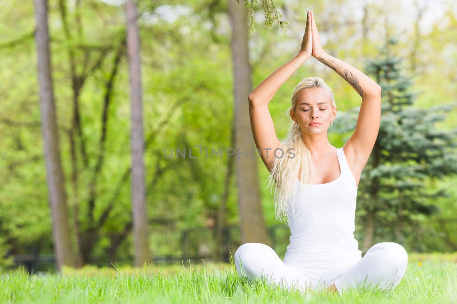 Young girl doing lotus yoga exercise in spring park