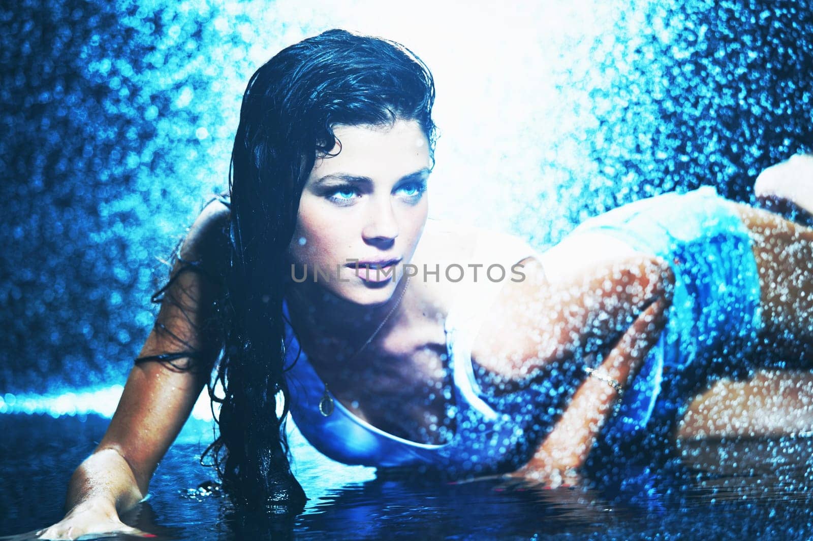 Young sexy woman, water studio photo in blue light