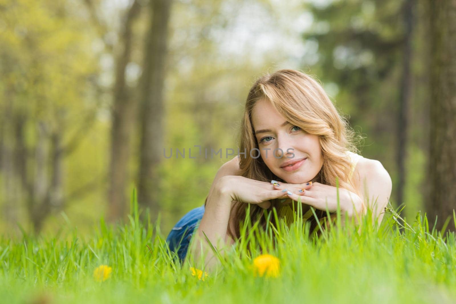 Woman lying on dandelions field by Yellowj