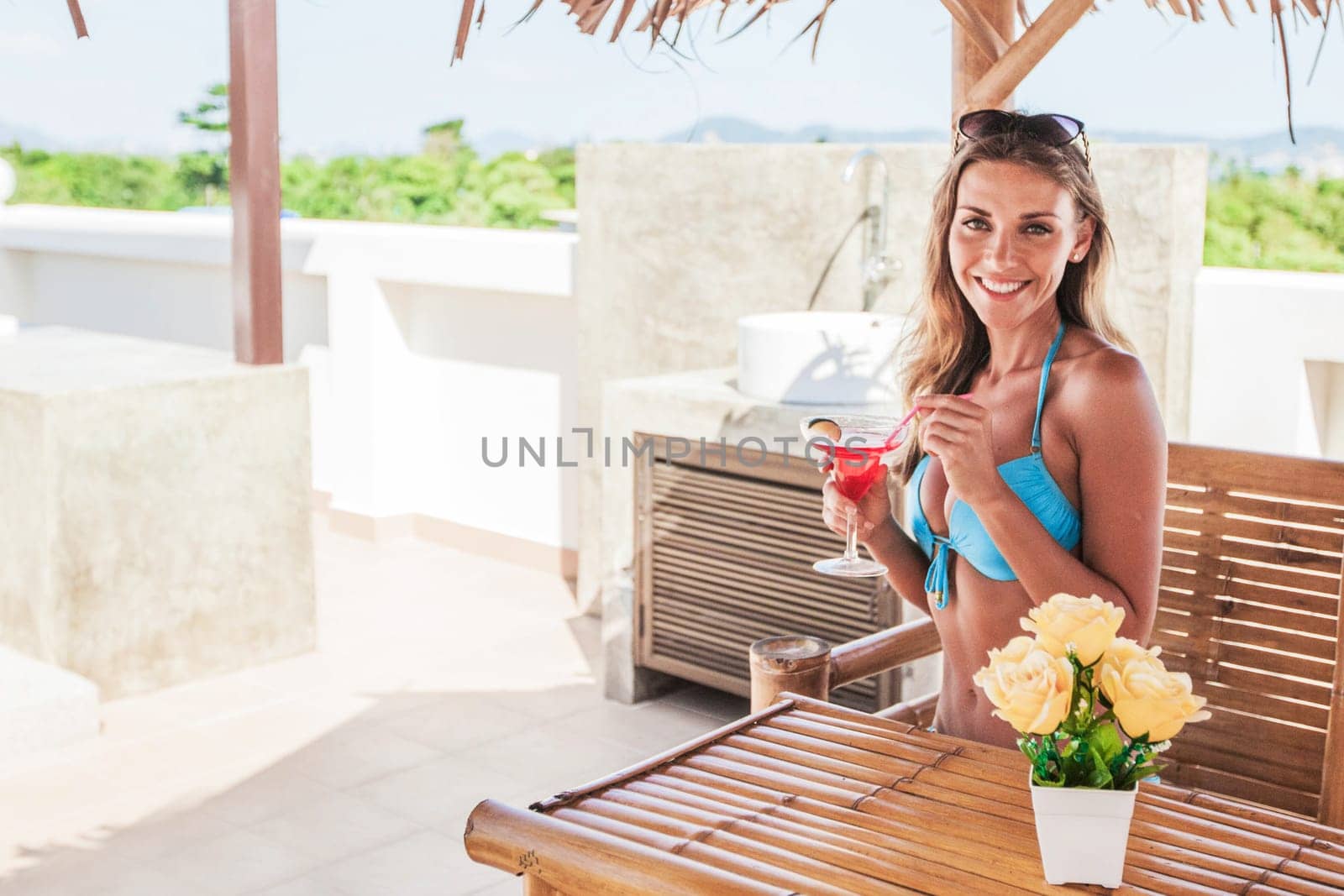 Beautiful girl in bikini drinking a cocktail at tourist resort cafe