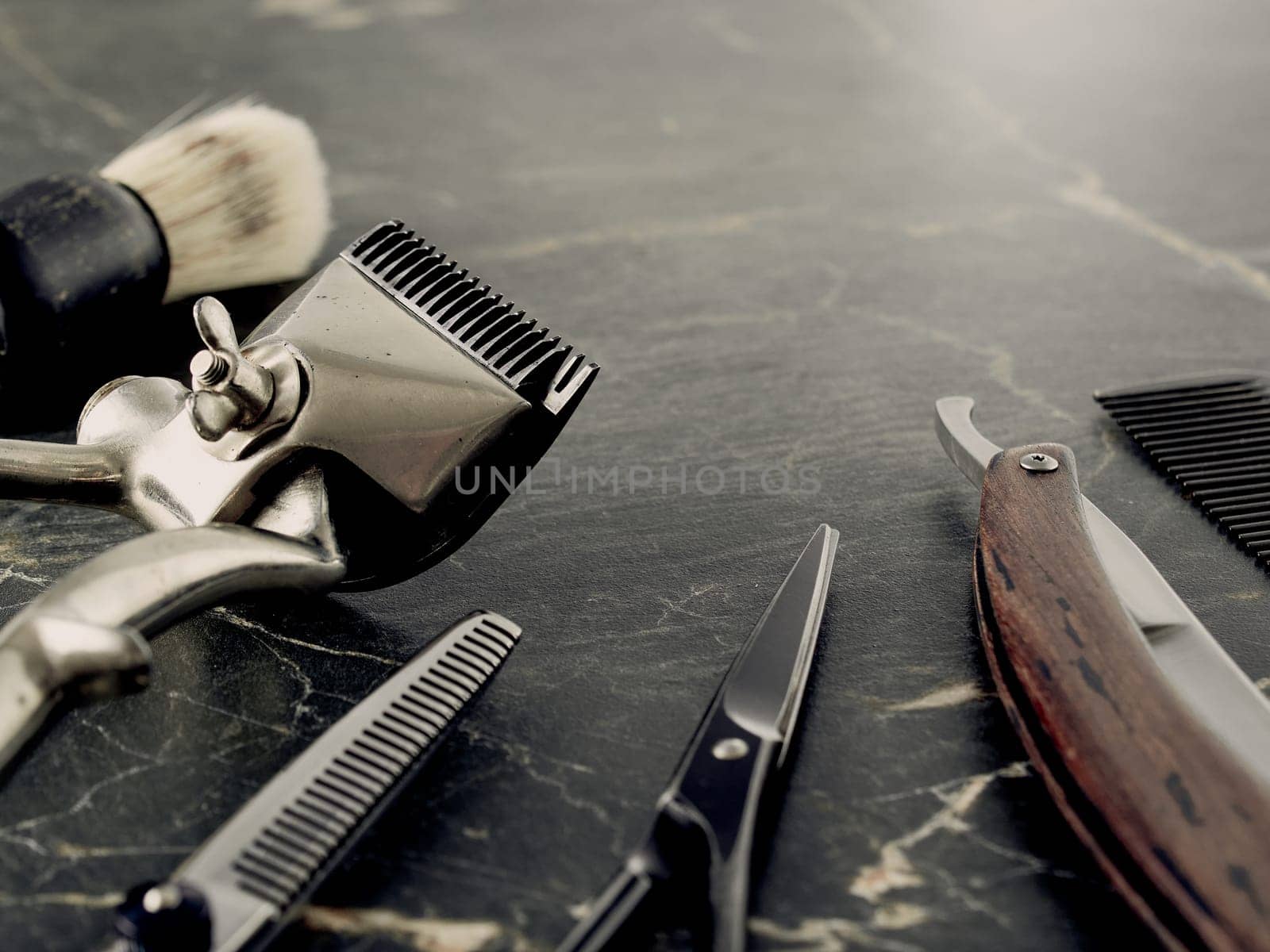 On a grey marble surface are old barber tools. Vintage manual hair clipper comb razor shaving brush shaving brush hairdressing scissors.