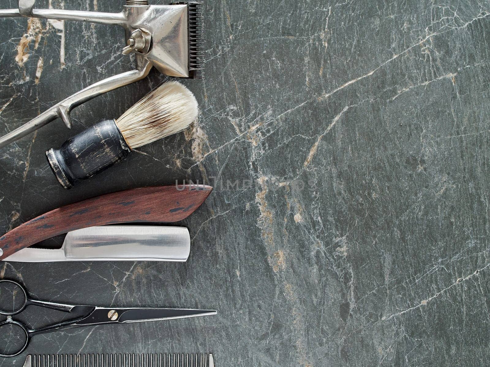 On a grey marble surface are old barber tools. Vintage manual hair clipper comb razor shaving brush shaving brush hairdressing scissors. top view. flat lay. copy space.