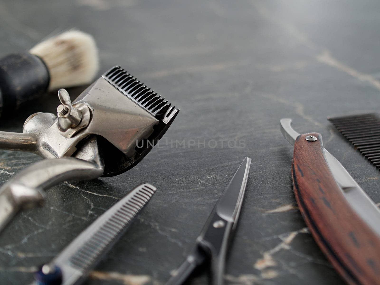 On grey marble surface are old barber tools. Vintage manual hair clipper comb razor shaving brush shaving brush hairdressing scissors.