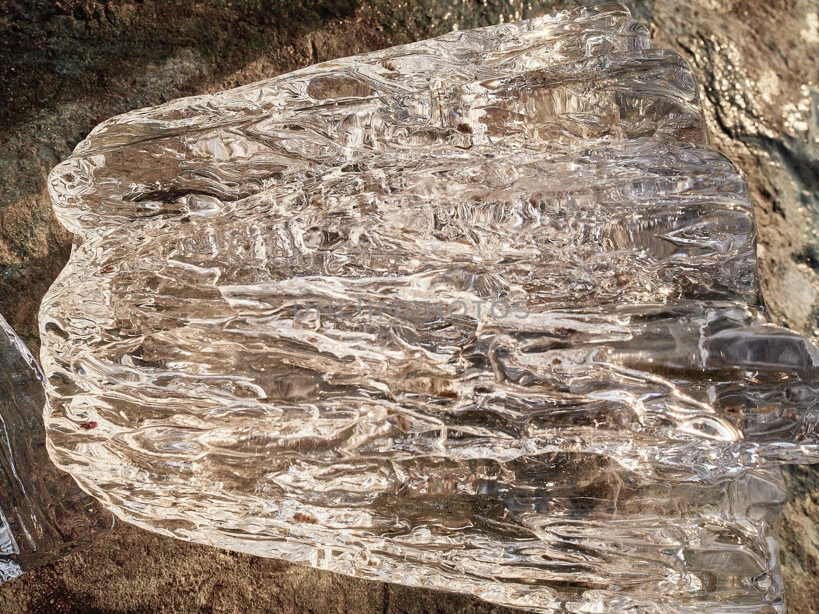 Natural crystal clear melting ice cubes on rock surface background. Vertical orientation