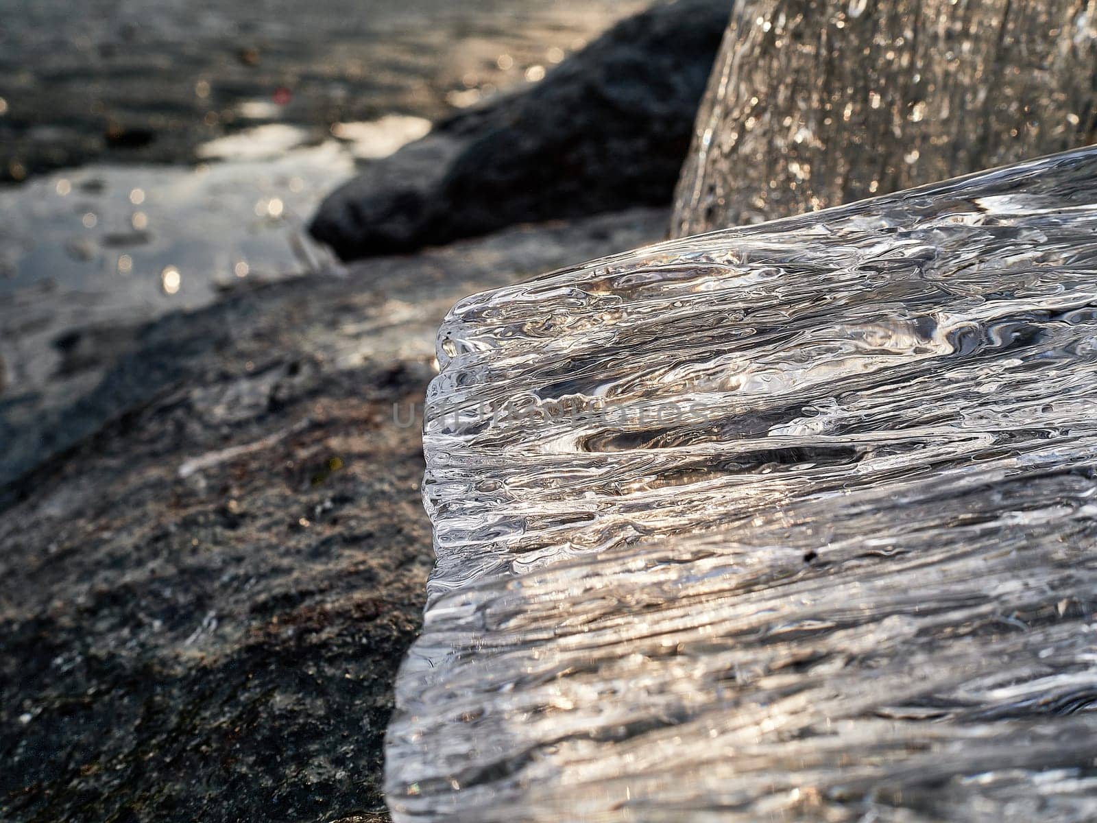 Natural crystal clear melting ice cubes on rock and reflection water surface background. Horizontal orientation.