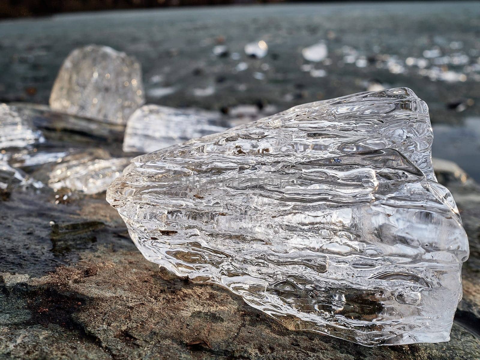 Natural crystal clear melting ice cubes on rock and reflection water surface background. Horizontal orientation.