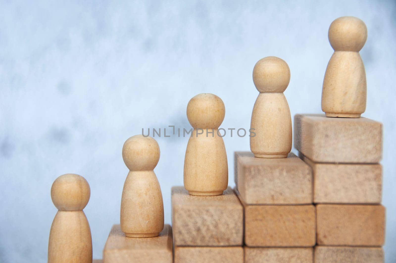 Wooden figure on top of stacking cubes representing goal achievement. Copy space, Goal achievement and leadership concept.