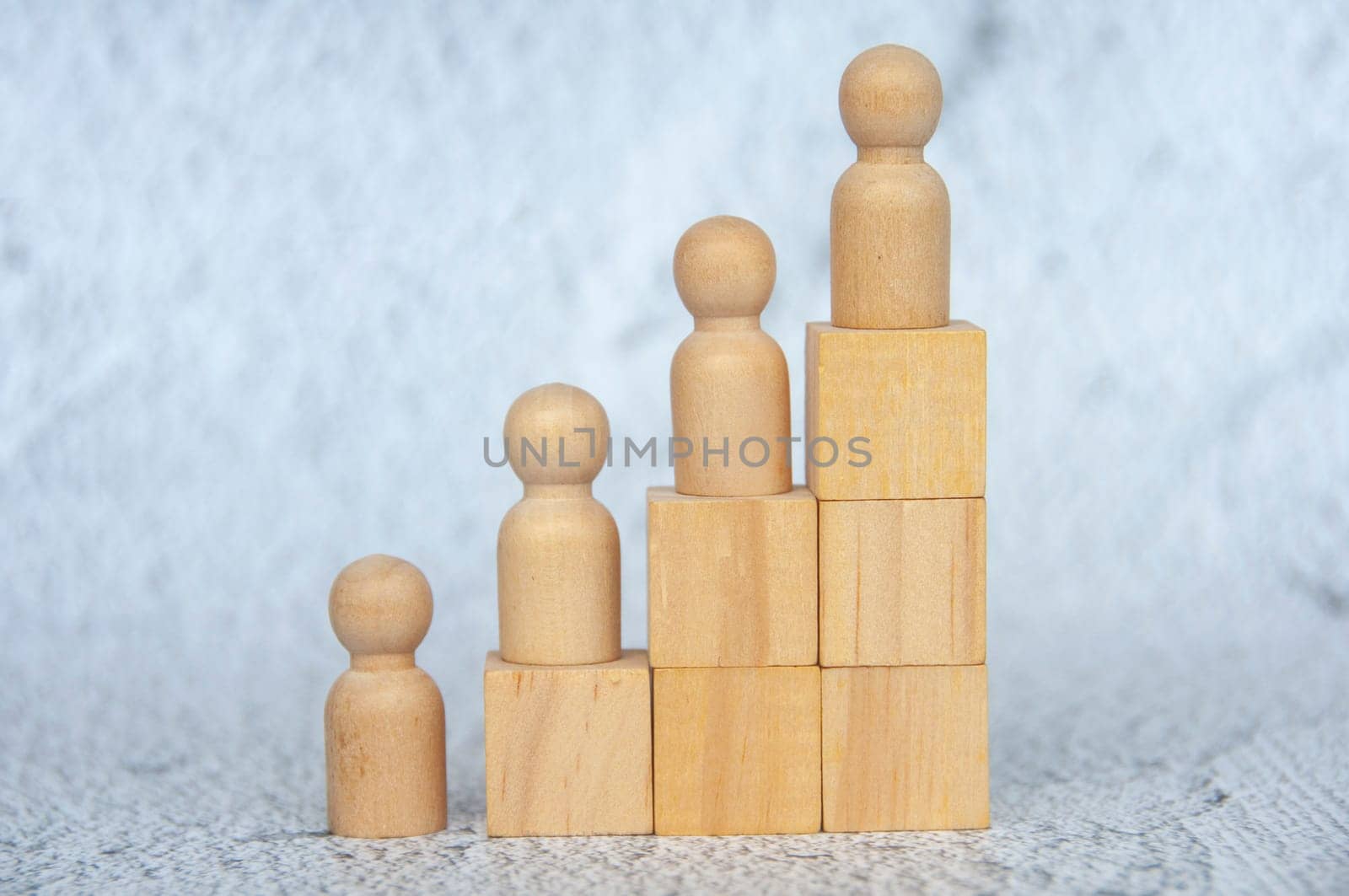 Wooden figure on top of stacking cubes representing goal achievement. Goal achievement and leadership concept