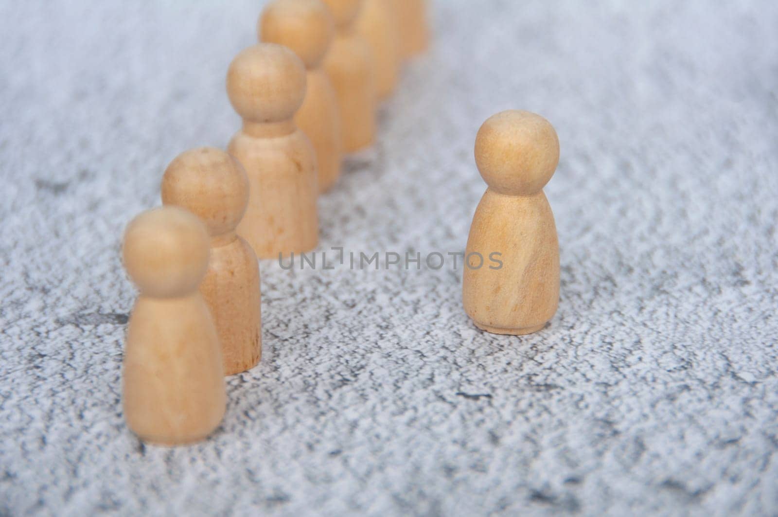 A wooden figure taking the first step out from the rest of the figure representing courage. Leadership concept.