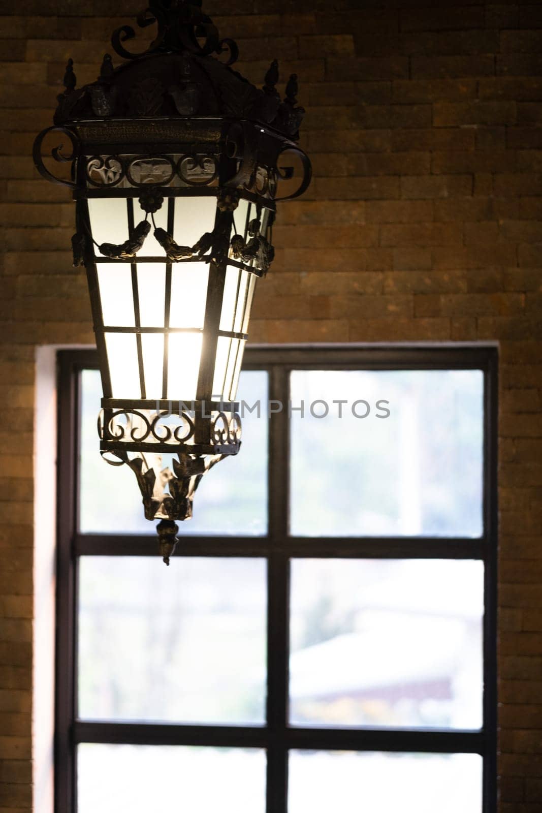 Old fashioned beautiful vintage lamp hangs from the ceiling, vintage fashioned lamp and window. High quality photo