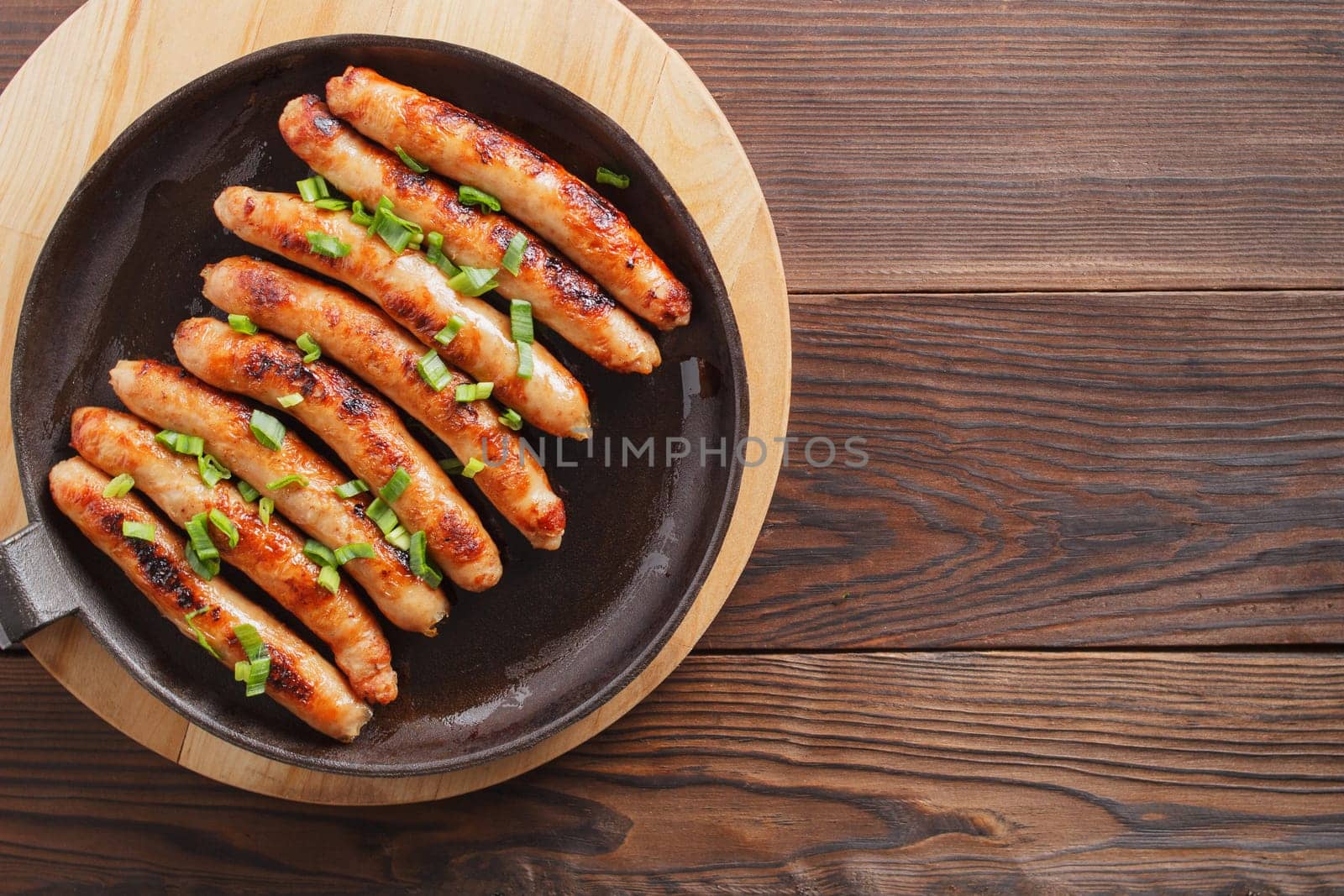 Delicious sausages cooked in a frying pan on a wooden table. copy space.