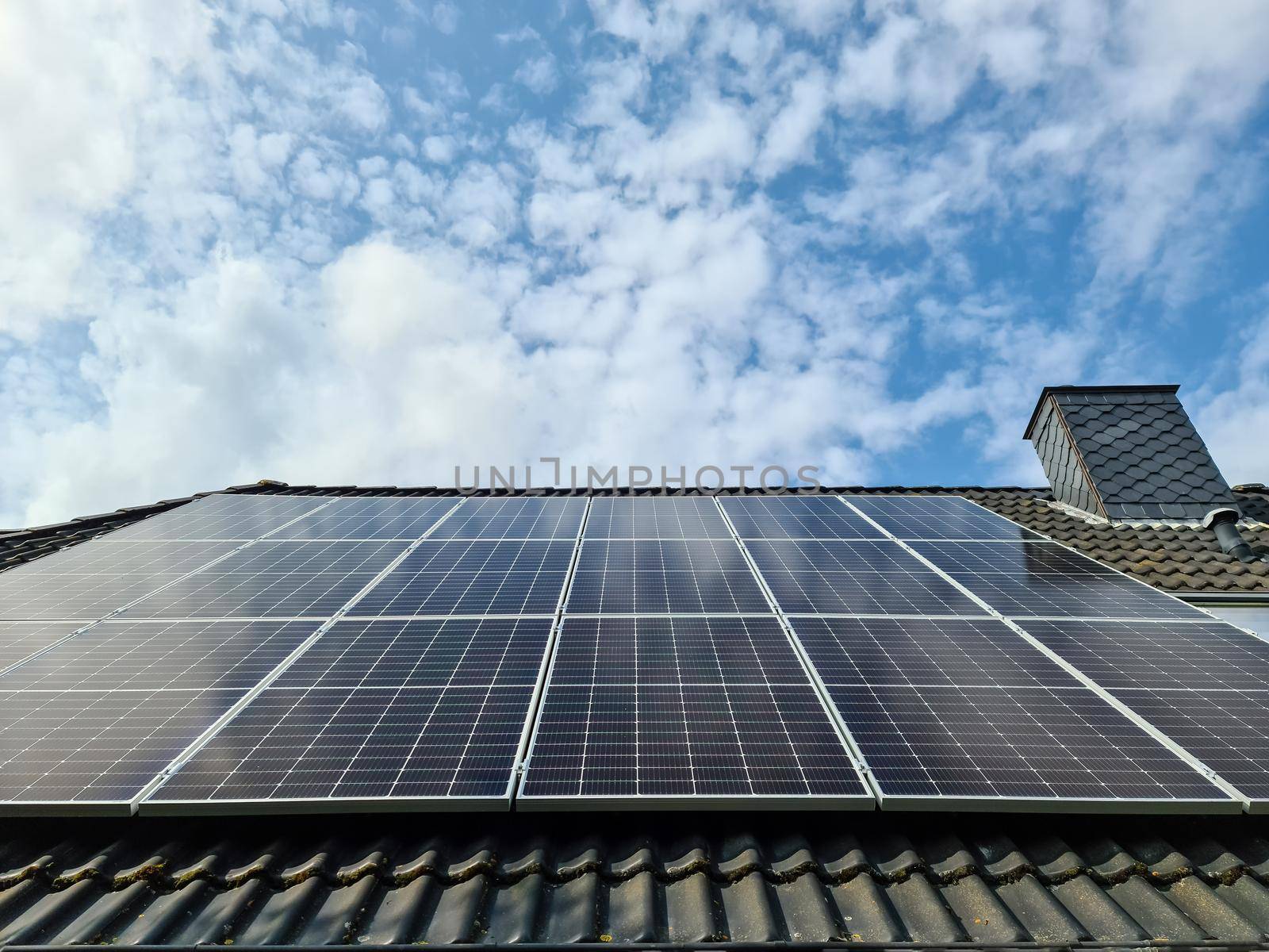 Solar panels producing clean energy on a roof of a residential house with cloud reflections