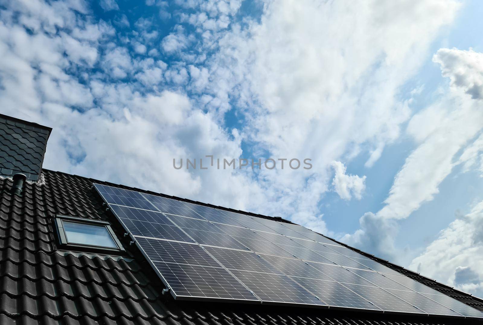 Solar panels producing clean energy on a roof of a residential house with cloud reflections