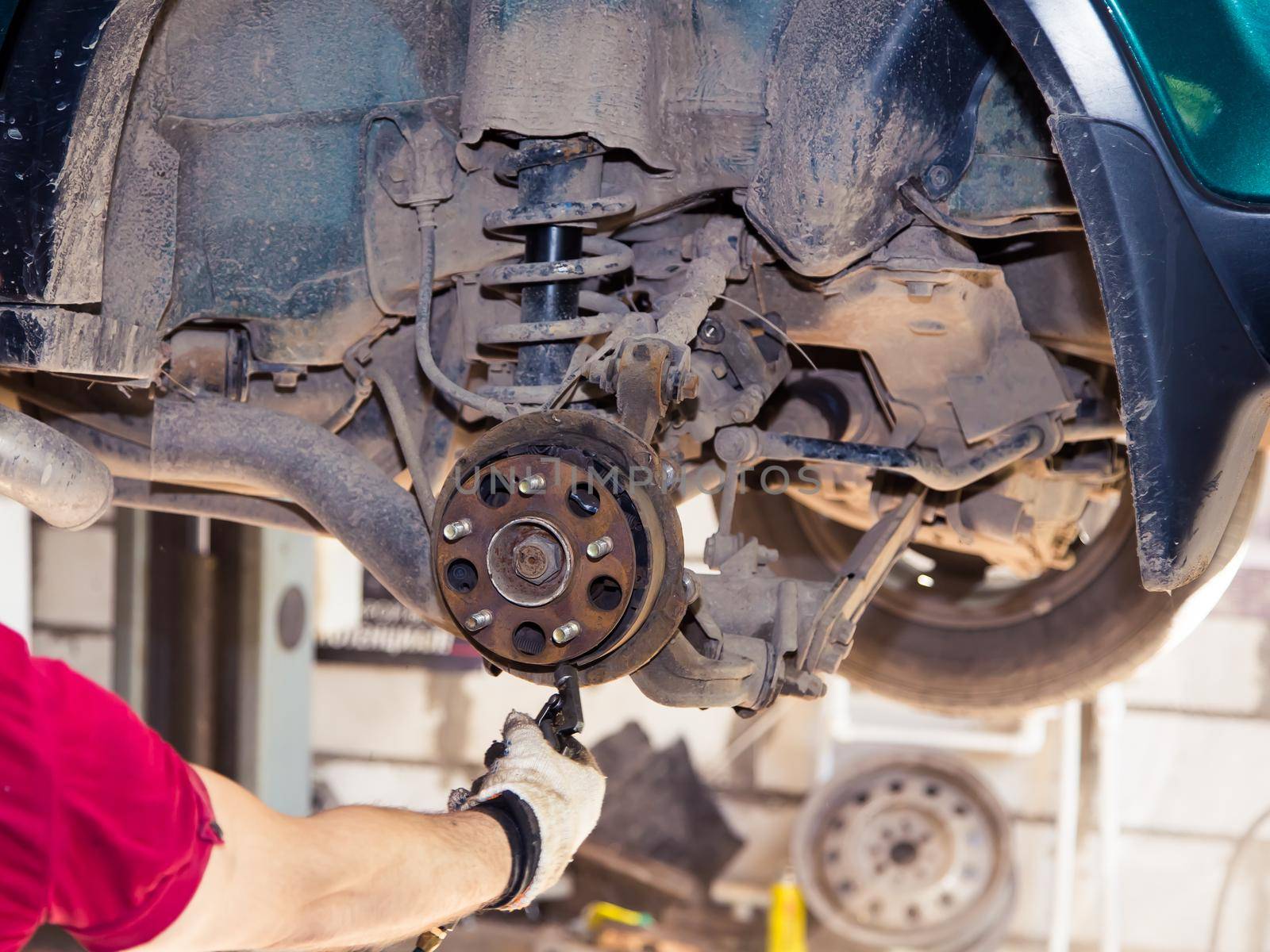 Hands blow off dirt from the worn rear wheel hub with a jet of air. In the garage, a person changes the failed parts on the vehicle. Small business concept, car repair and maintenance service.