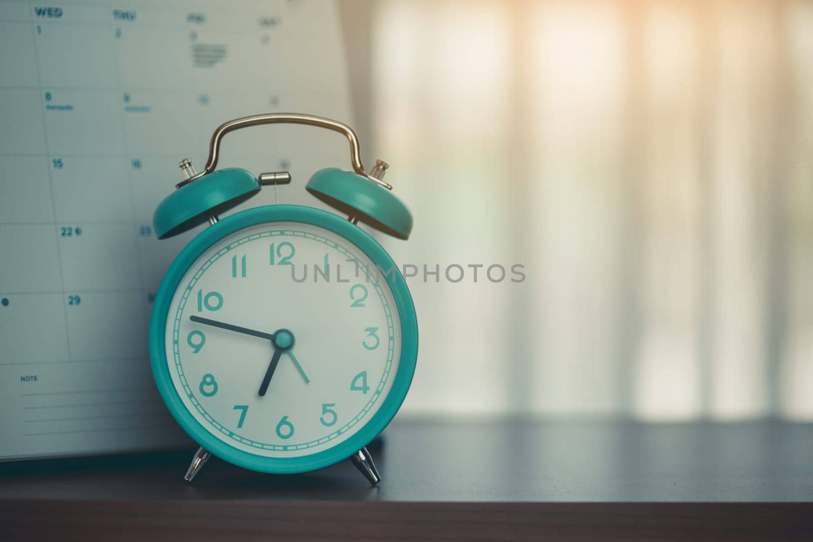 An alarm clock with calendar on the desk for the concept of time and date management.