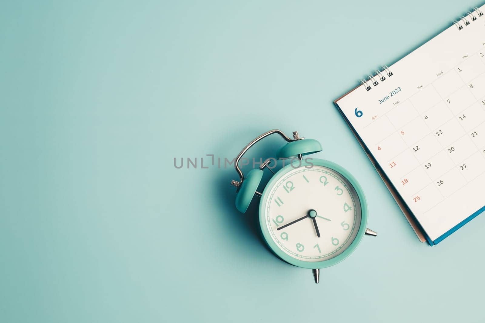 An alarm clock with calendar on blue background for the concept of time and date management.