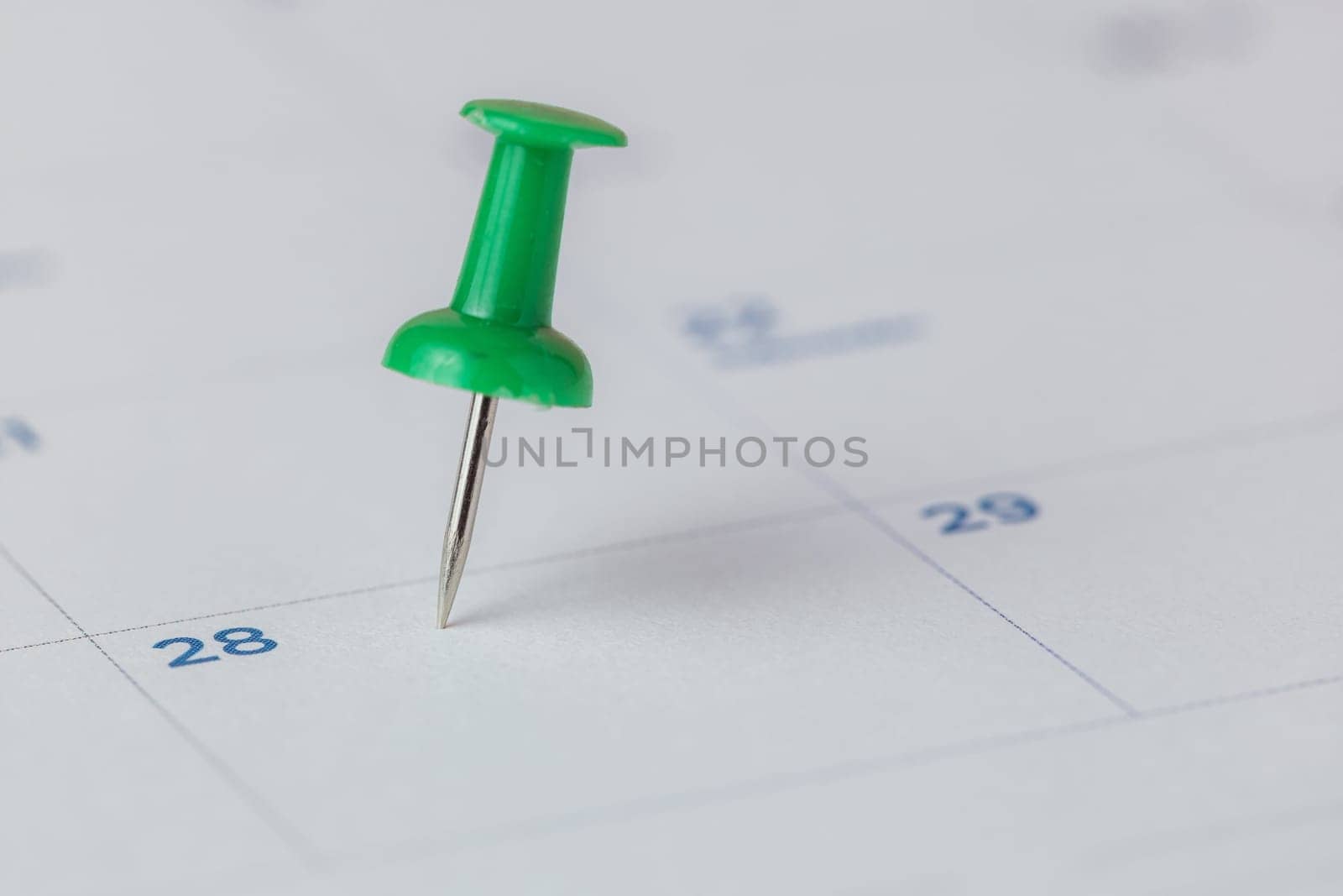 Selective focus of a green push pin marking on calendar for the concept of appointment, reminder and important note.