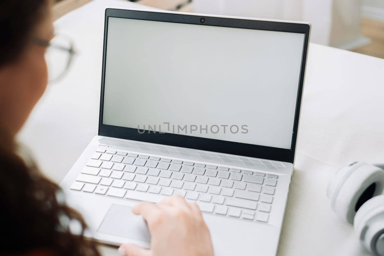 Over shoulder view of woman student elearning looking at white mock up blank screen using laptop computer learning online, remote working concept. Website mockup display template for ads concept
