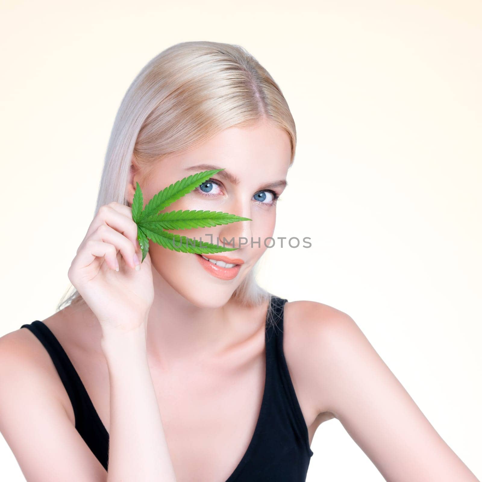 Personable white blond hair woman holding CBD leaf in isolated background. by biancoblue
