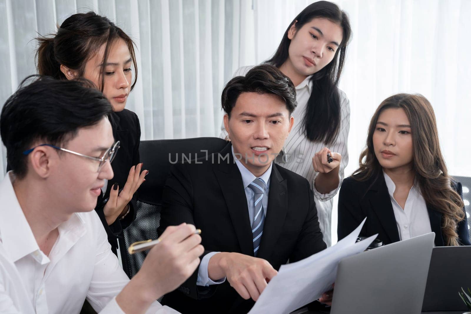 Harmony in office concept as business people analyzing dashboard paper together in workplace. Young colleagues give ideas at manager desk for discussion or strategy planning about project.