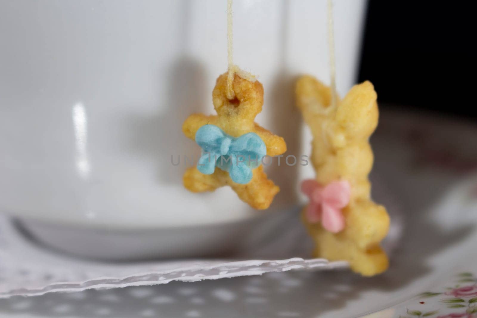 close-up of two bunny-shaped candies hanging from an old-fashioned teacup. High quality photo