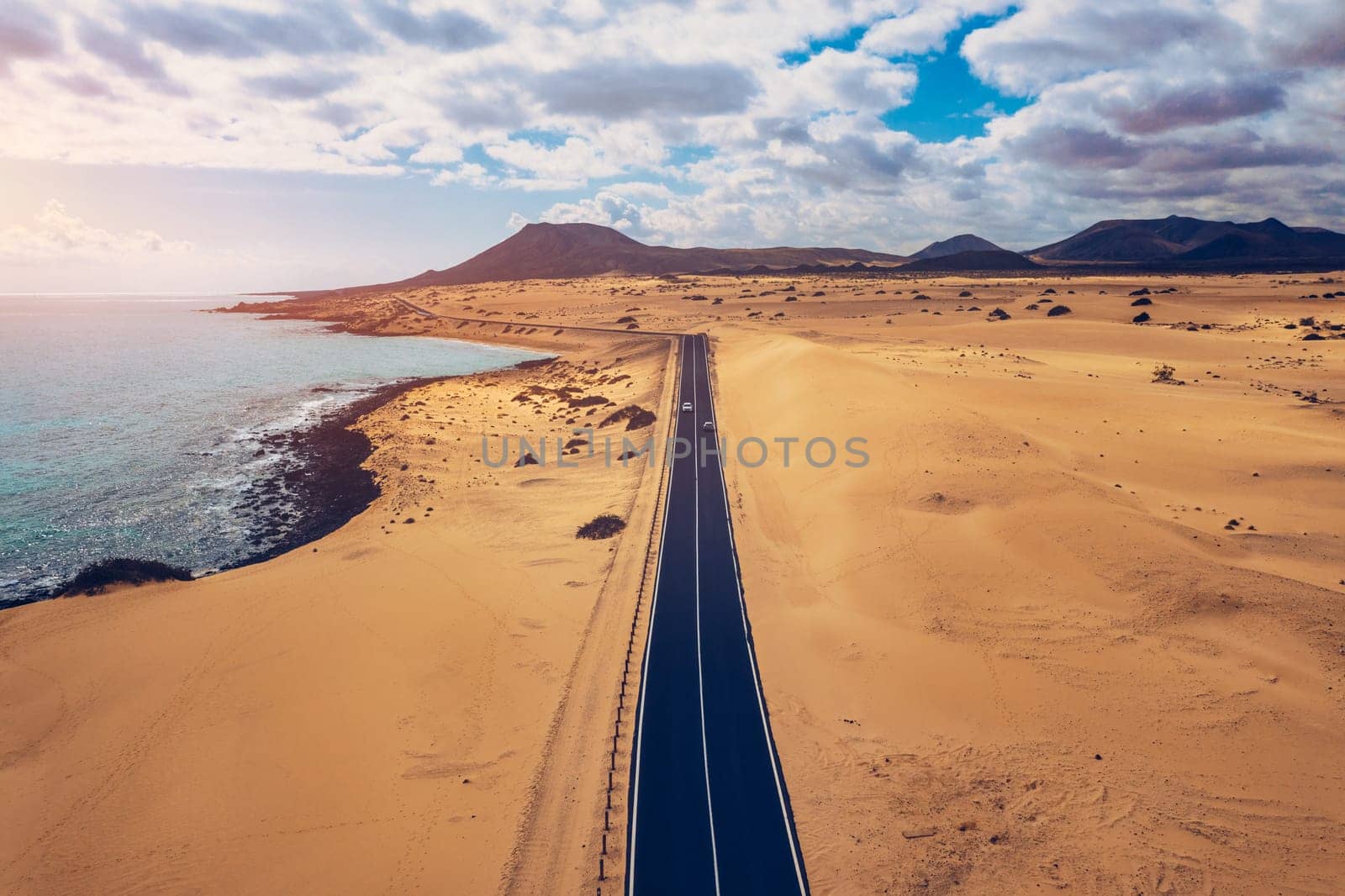 Fuerteventura, Corralejo sand dunes nature park. Beautiful Aerial Shot. Canary Islands, Spain. Aerial view of an empty road through the dunes at the sunset. Fuerteventura, Canary Islands, Spain.