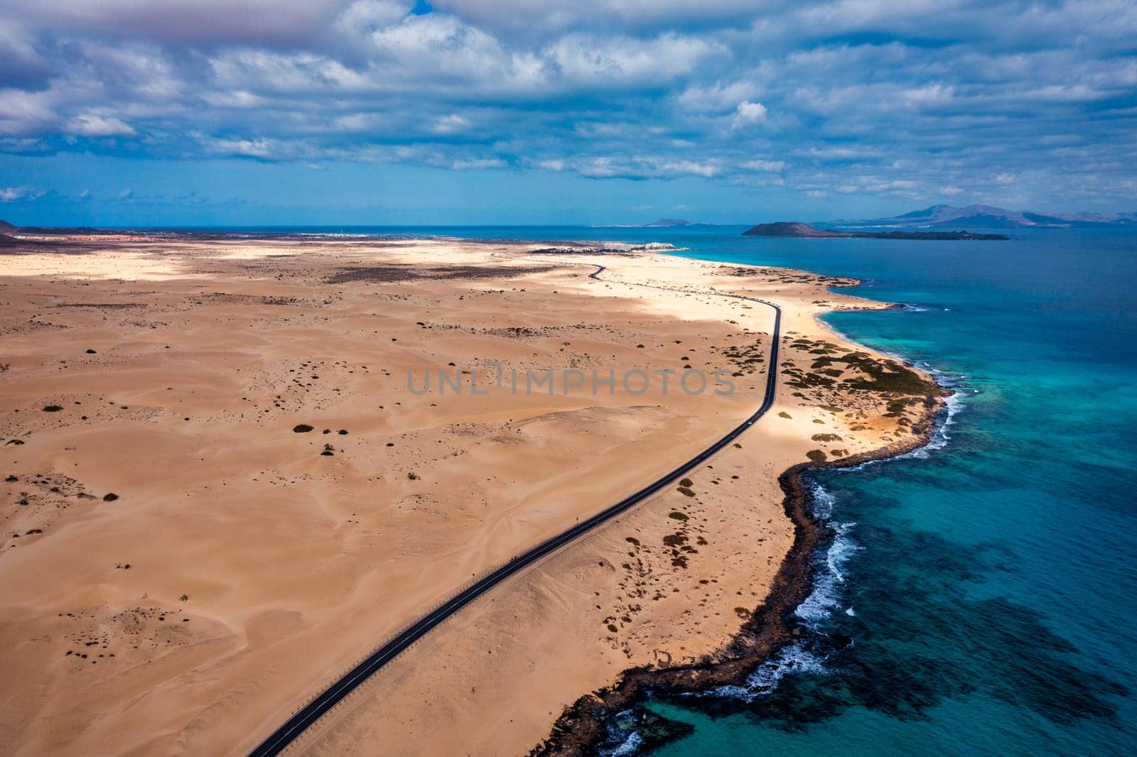 Fuerteventura, Corralejo sand dunes nature park. Beautiful Aerial Shot. Canary Islands, Spain. Aerial view of an empty road through the dunes at the sunset. Fuerteventura, Canary Islands, Spain.