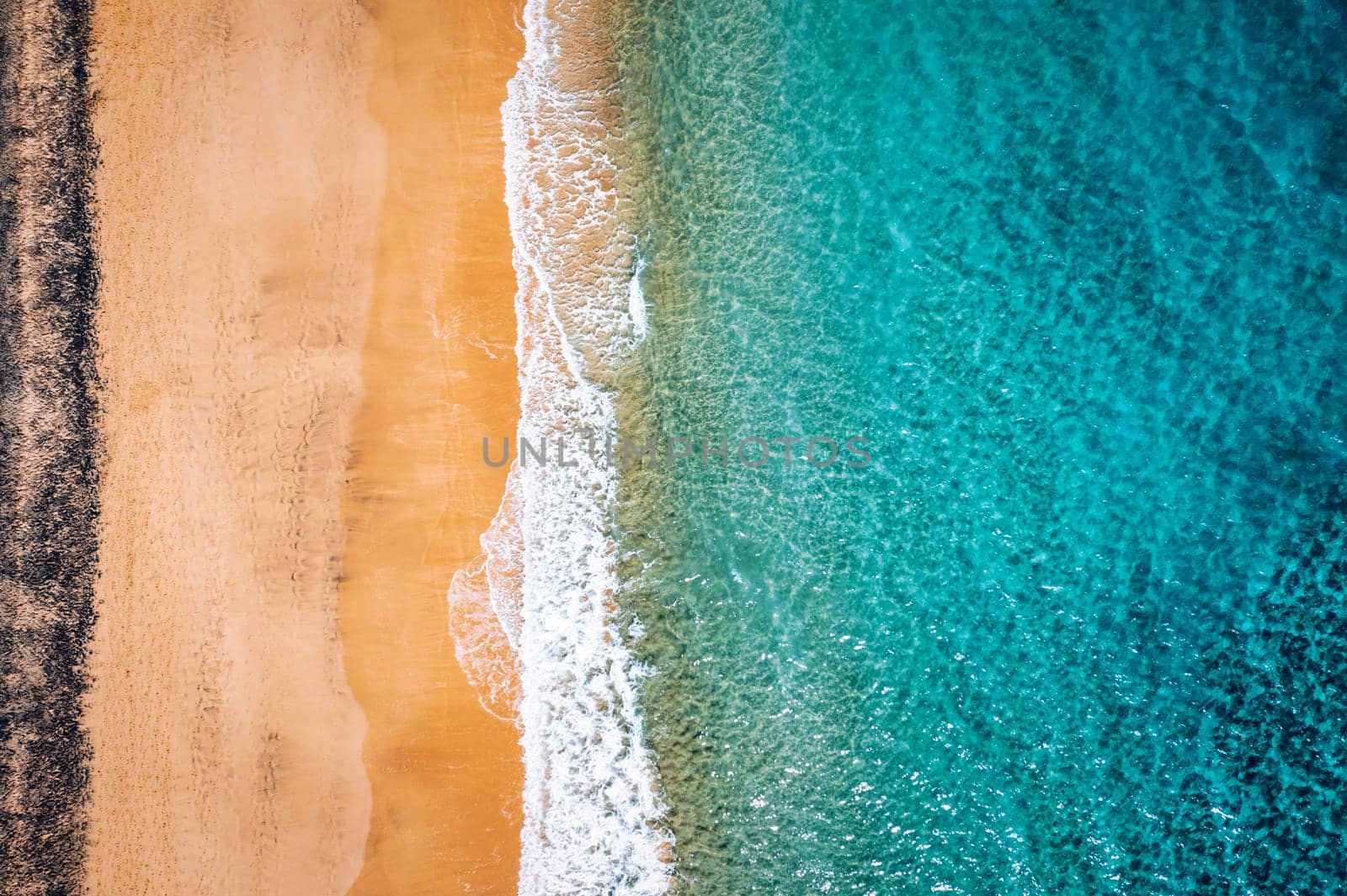 Beach with turquoise water on Fuerteventura island, Spain, Canary islands. Aerial view of sand beach, ocean texture background, top down view of sea waves by drone. Fuerteventura, Spain.