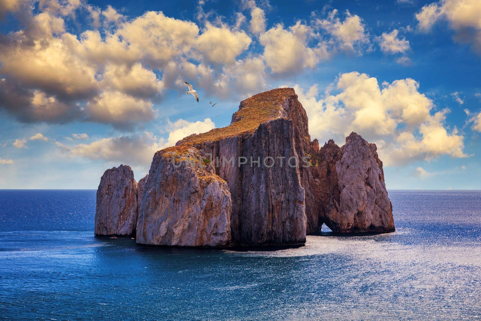 High cliffs of Mediterranean coast, "Pan di Zucchero" stack rock in Masua, west coast of Sardinia, Italy. Concali Su Terrainu with Porto Corallo on background. Sardinia island, Italy, Europe.