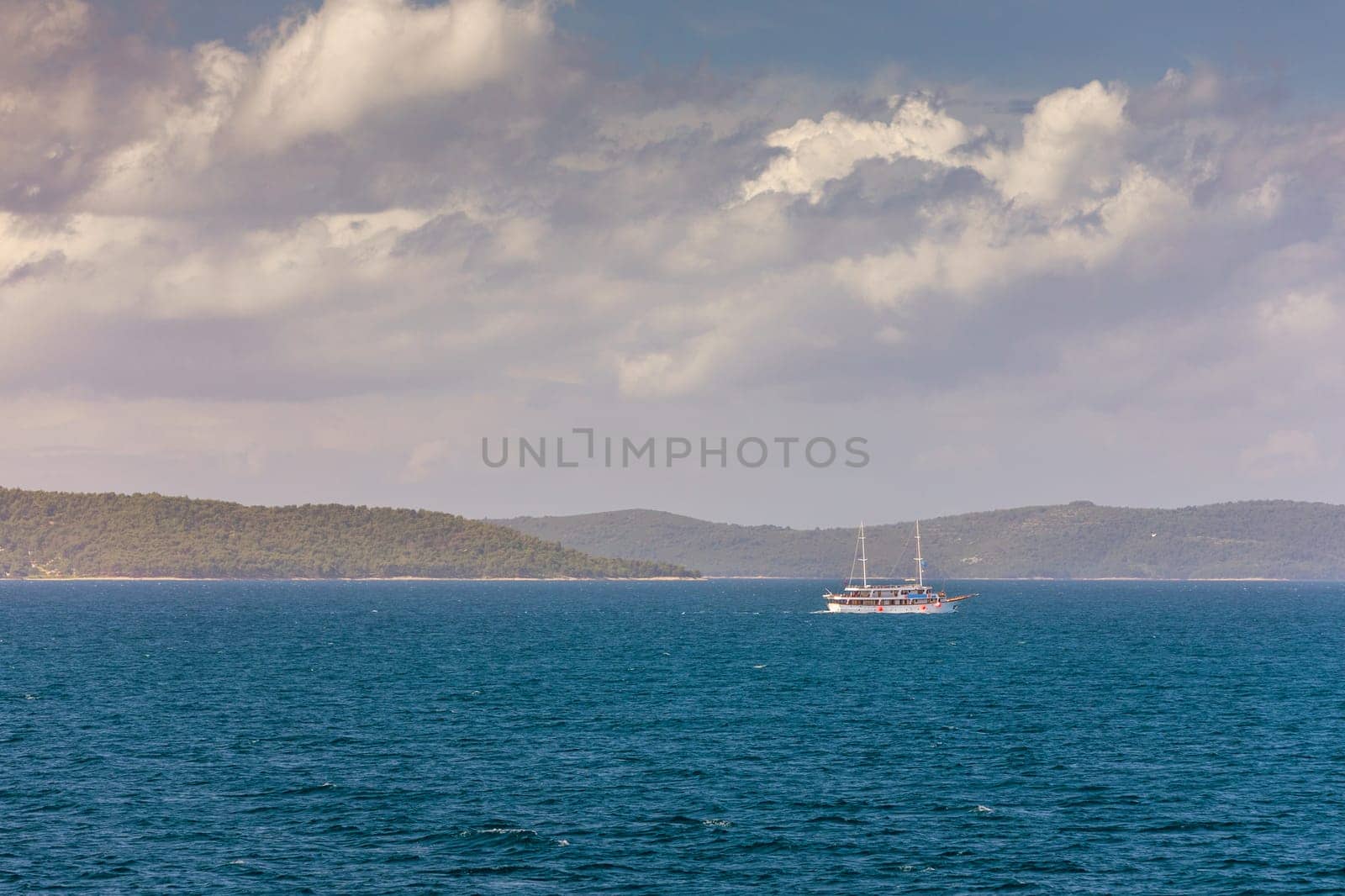 Sailboat in the sea in the evening sunlight with mountains background, luxury summer adventure, active vacation in Mediterranean sea, Croatia. Sailing ship luxury yacht with white sails in the Sea. 