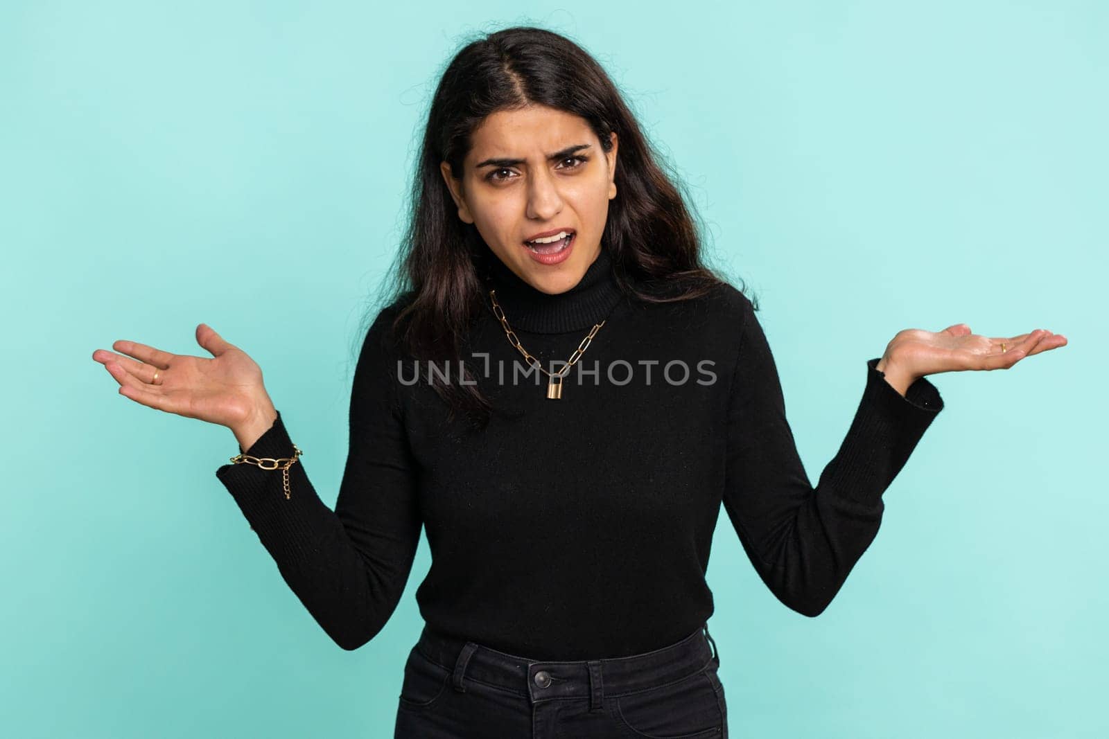 What Why. Sincere irritated indian woman raising hands in indignant expression asking reason of failure demonstrating disbelief irritation by trouble. Pretty confused hindu girl on blue background