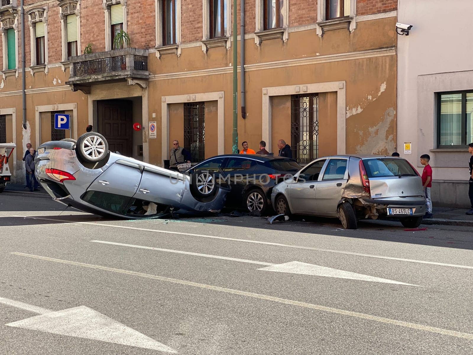 Cremona, Italy - 18th April 2023 just rolled over crashed car after an accident, police officer helping with traffic