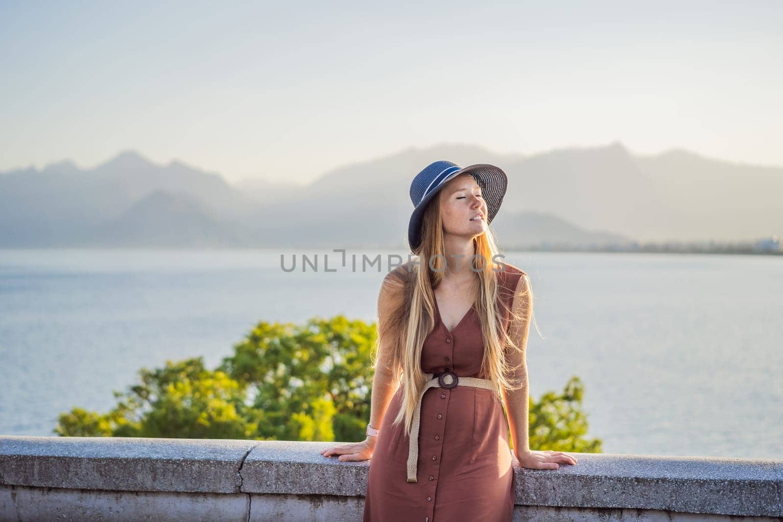 Happy woman tourist on background of Antalya sea and mountain views, sea in Turkey Antalya City. female tourist traveler discover interesting places and popular attractions and walks in the old city Kalechi of Antalya, Turkey. Turkiye.