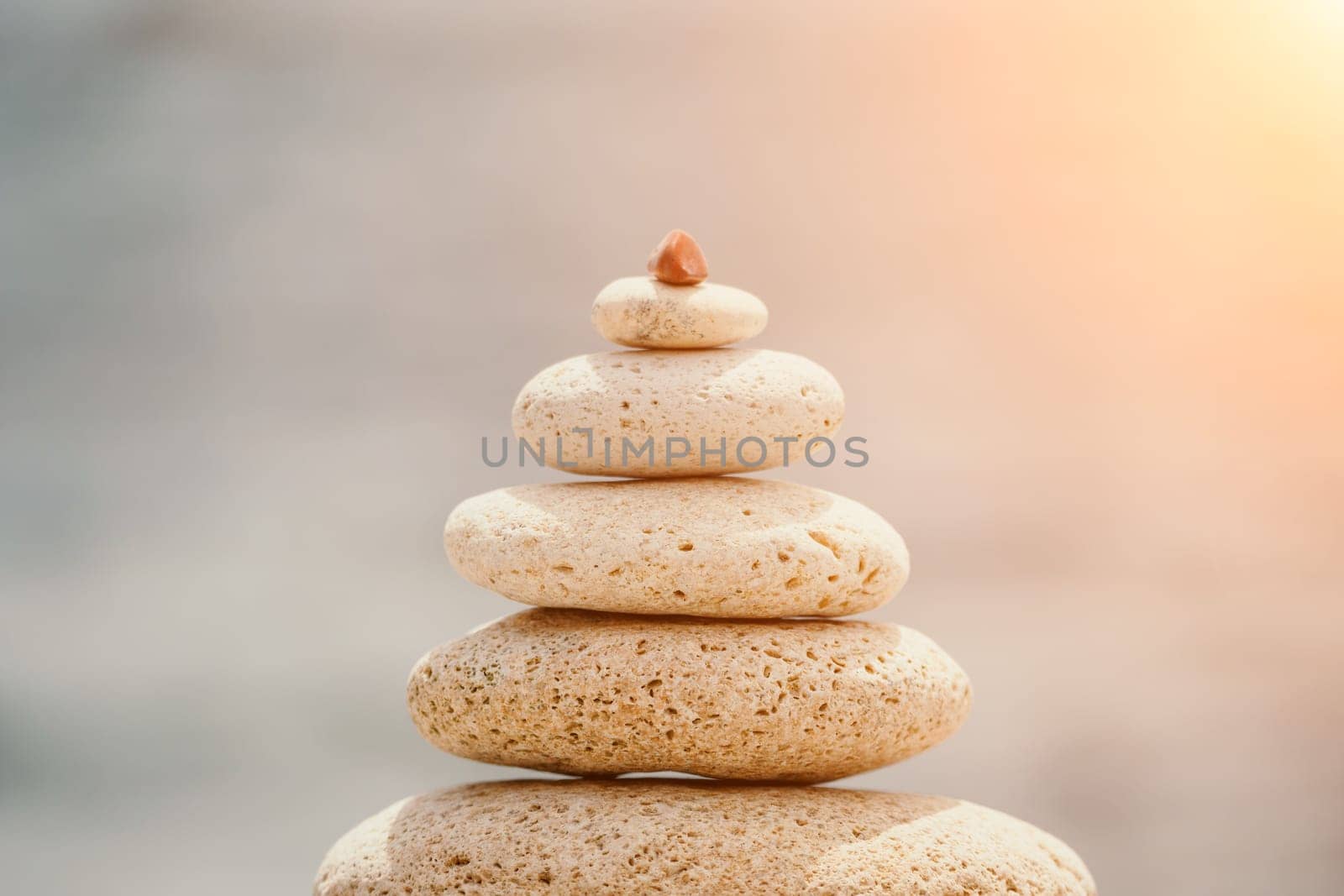 Calm pebble beach with pyramid stones and warm sunset on the sea background. Perfect travel destination for happy holidays, meditation, and relaxation at spa. concept of calmness and tranquility. by panophotograph