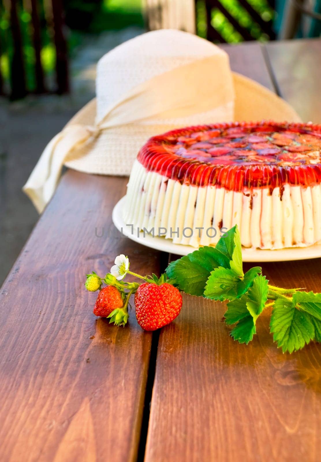 Cake with strawberries and whipped cream decorated with leaves on wooden background