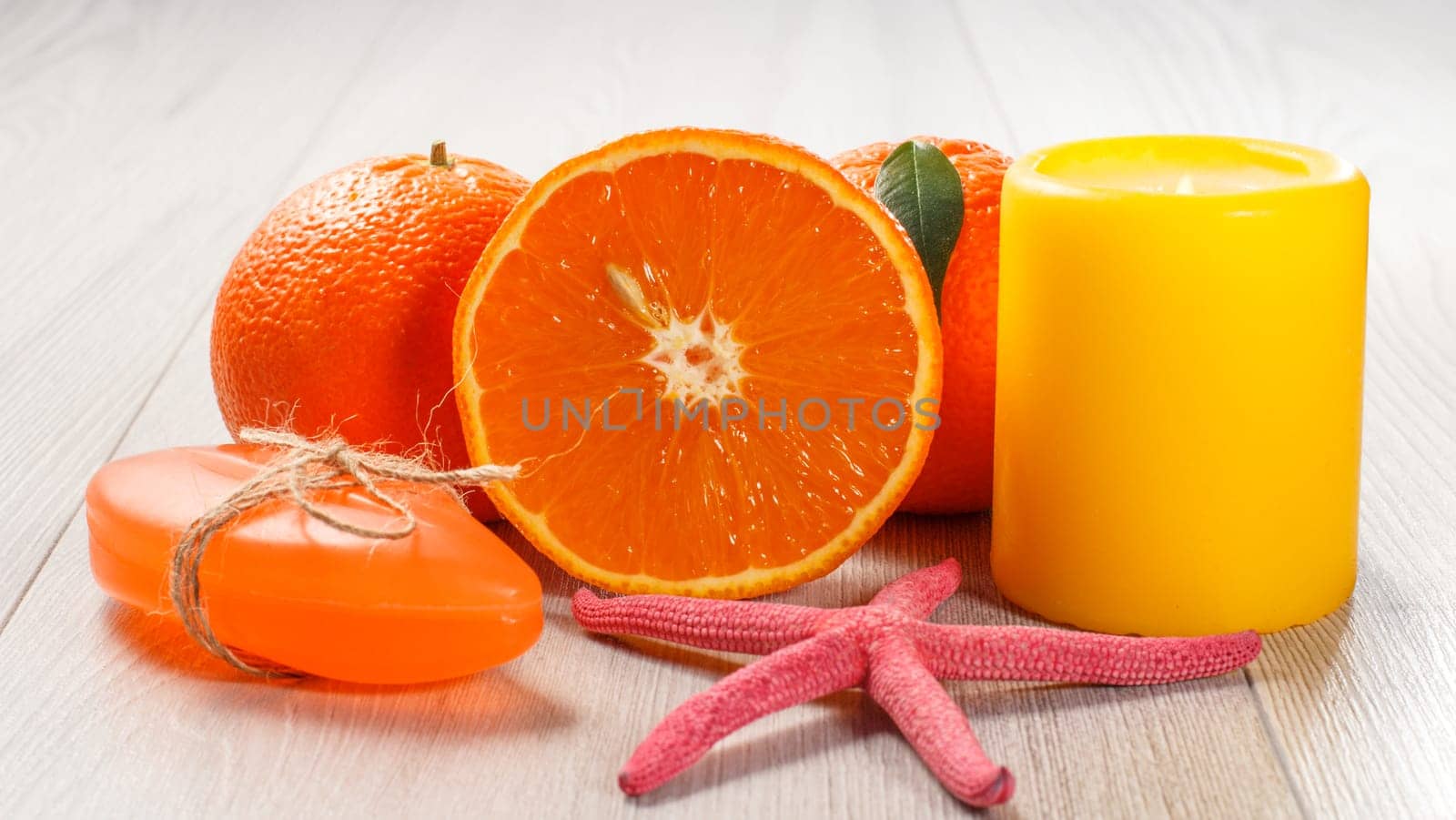 Cut orange with two whole oranges, soap, starfish and burning candle. by mvg6894