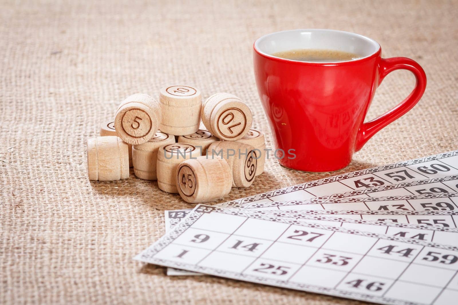 Board game lotto on sackcloth. Wooden lotto barrels and game cards for a game in lotto with red cup of coffee.