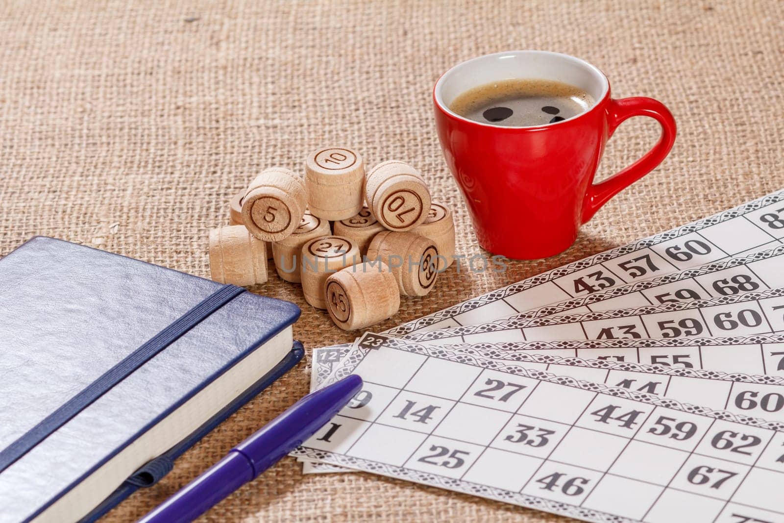 Board game lotto on sackcloth. Wooden lotto barrels and game cards for a game in lotto with a cup of coffee and a notebook with pen.