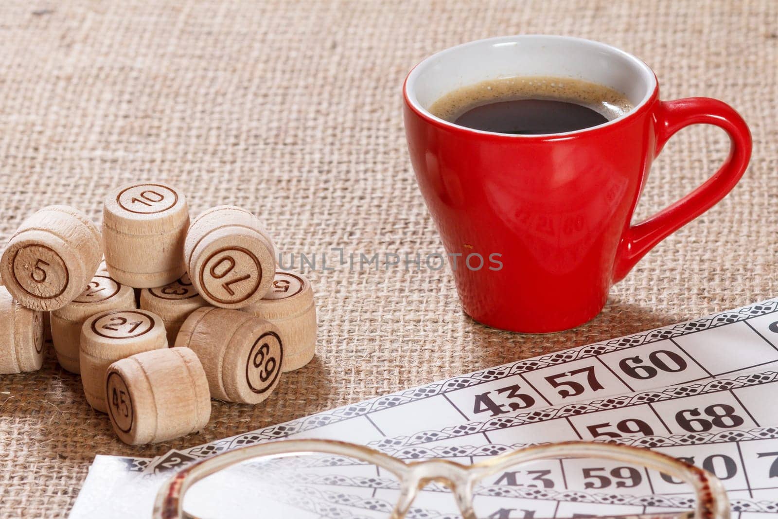 Board game lotto on sackcloth. Wooden lotto barrels and game cards for a game in lotto with red cup of coffee and glasses.
