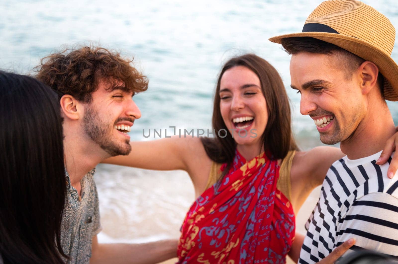 Group of friends laugh together embracing at the beach. Friendship and summer vacations. Lifestyle concept.