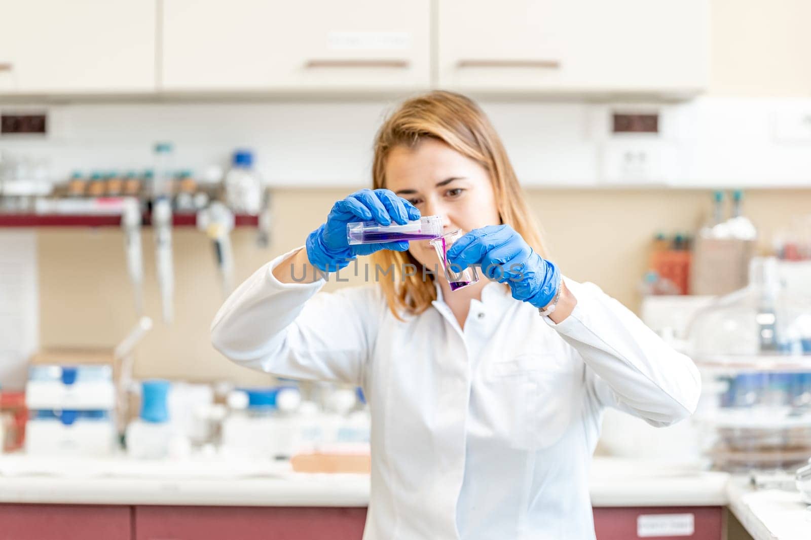 young female scientist conducts chemical experiments in a research laboratory by Edophoto