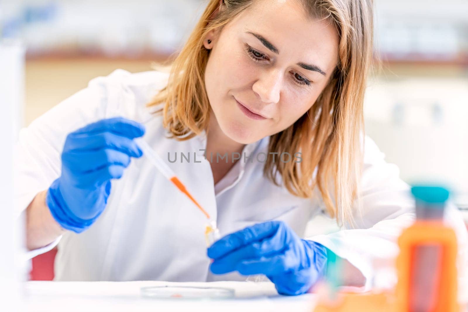 young caucasian blond female scientist conducts chemical experiments in a research laboratory by Edophoto