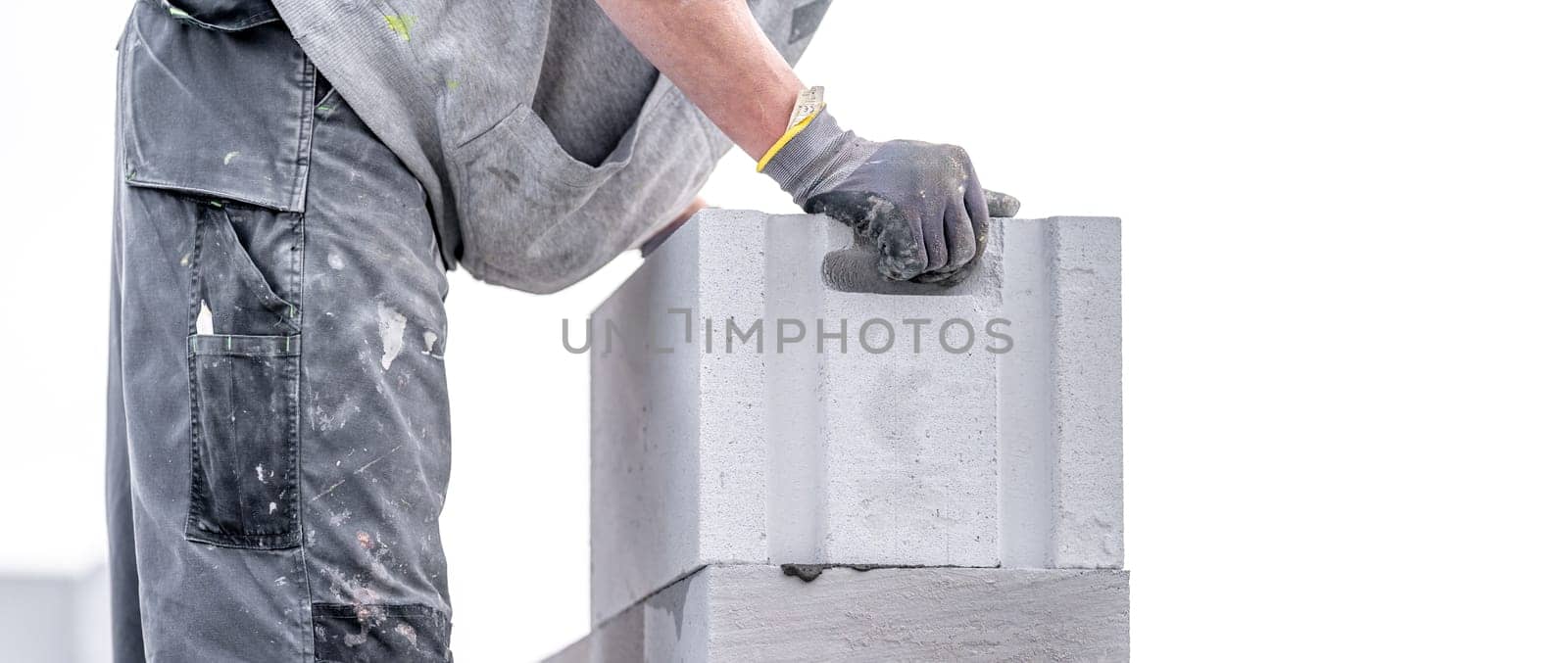 a mason builds the wall of a building from concrete bricks and blocks by Edophoto