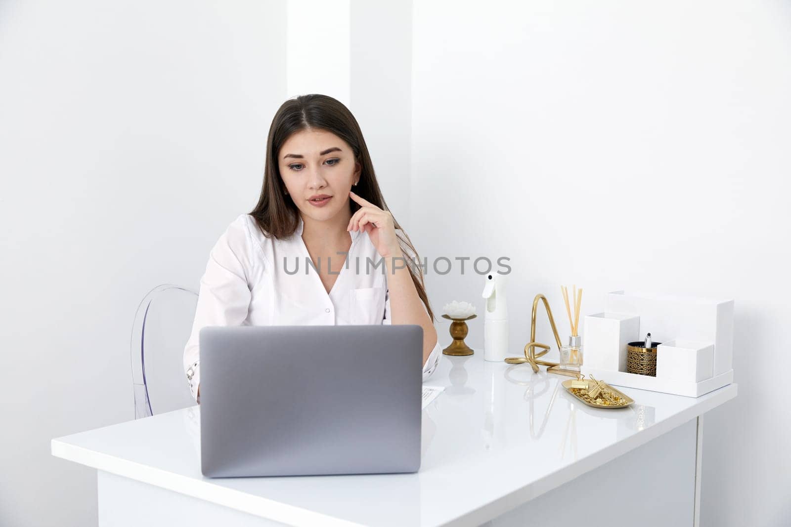 Portrait of female doctor talking to online patient on laptop screen sitting at clinic office desk giving online consultation for domestic health treatment by Mariakray