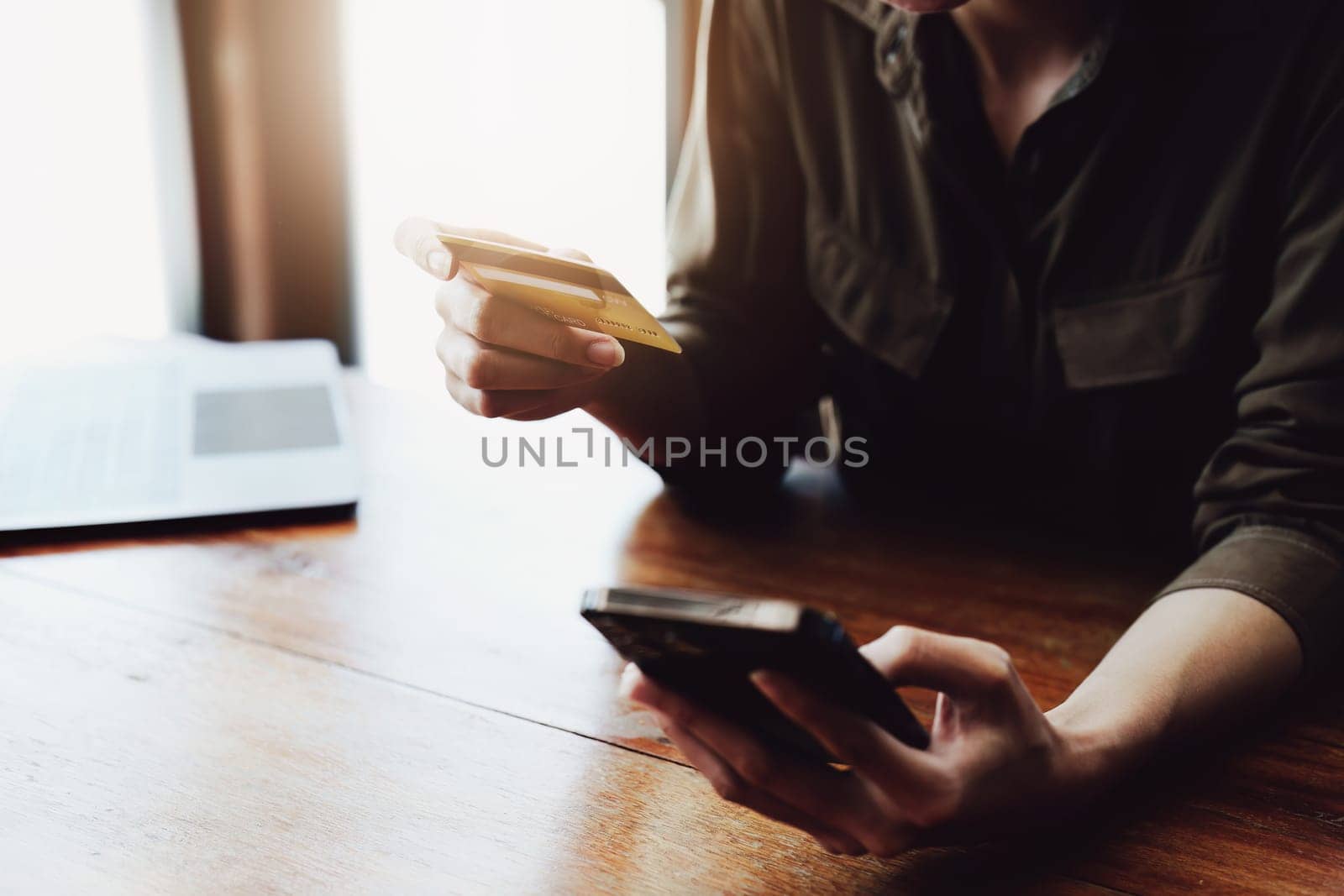 Portrait of young Asian woman using credit card and phone for online shopping by Manastrong