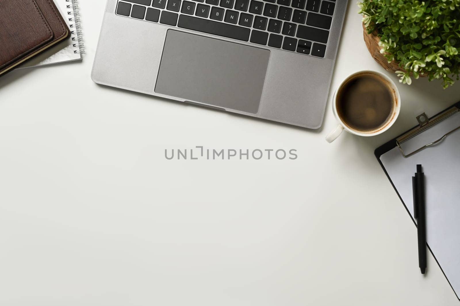 Modern white office desk table with laptop computer, cup of coffee and notebook. Top view with copy space, flat lay. by prathanchorruangsak