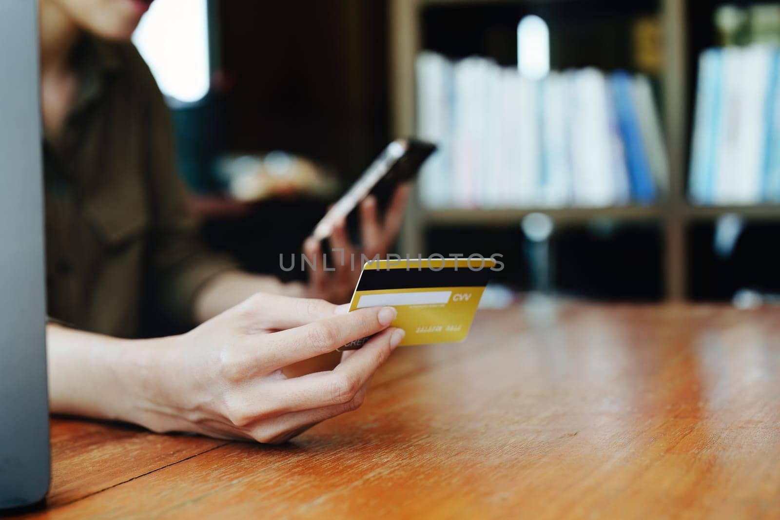 Portrait of young Asian woman using credit card and phone for online shopping.