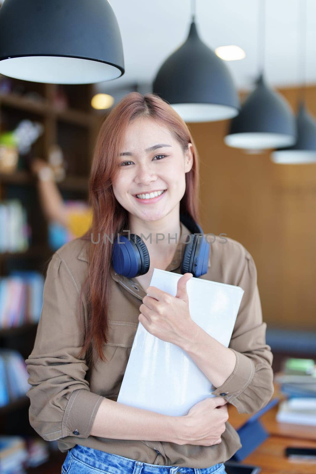 A portrait of a young Asian woman with a smiling face looking for a textbook in the library by Manastrong
