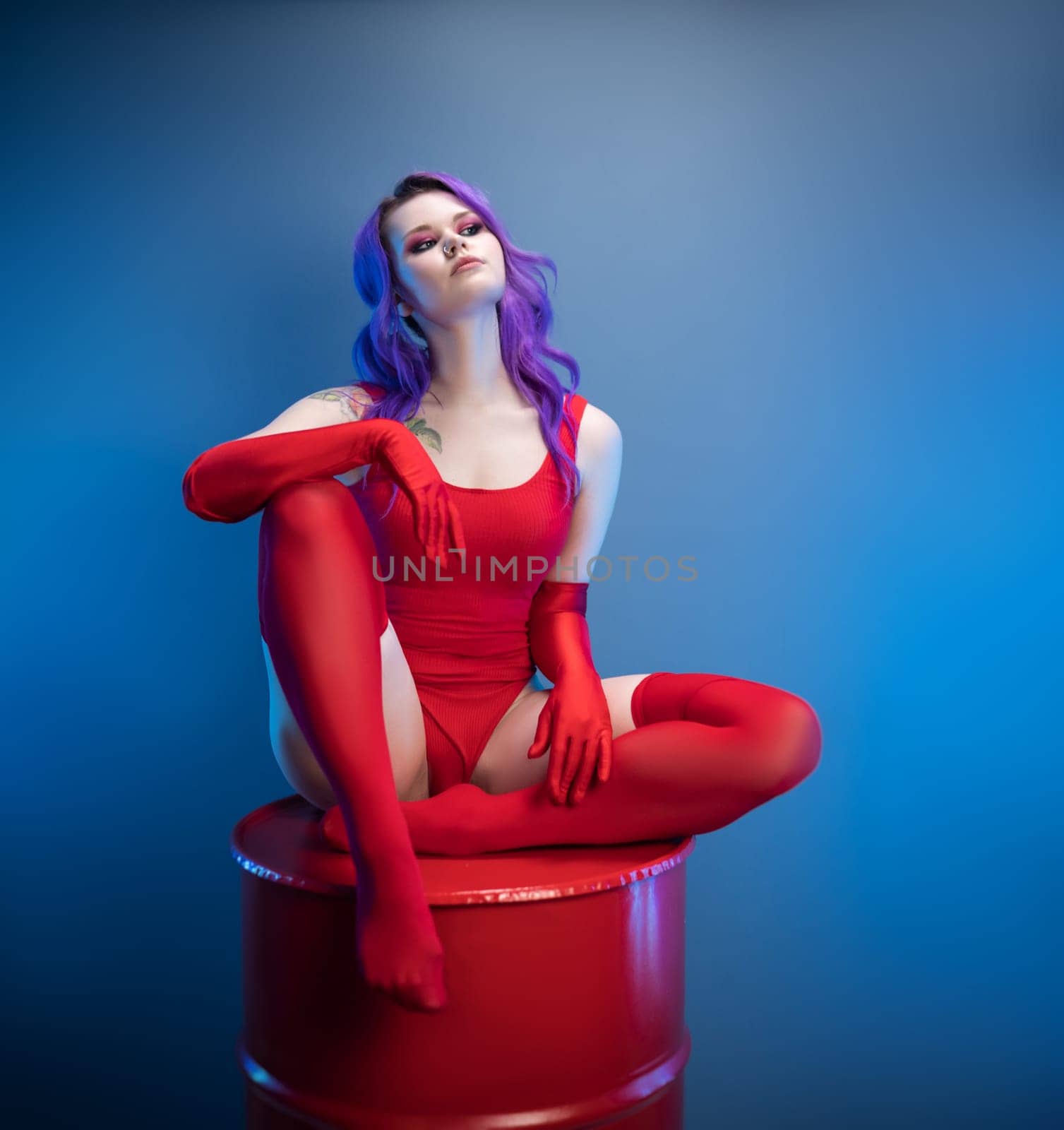 sexy girl in a red bodysuit, stockings and red gloves poses erotically on a blue background of a copy paste by Rotozey